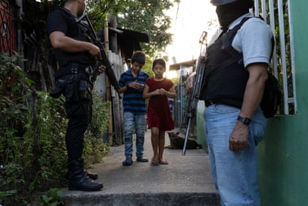 Residents in a low-income settlement (controlled by MS 13) pass by a police patrol, San Martín, San Salvador.