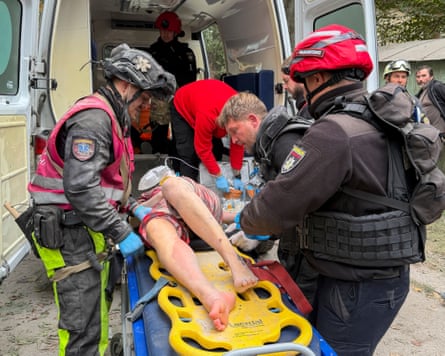 An injured woman is wheeled to an ambulance by medics