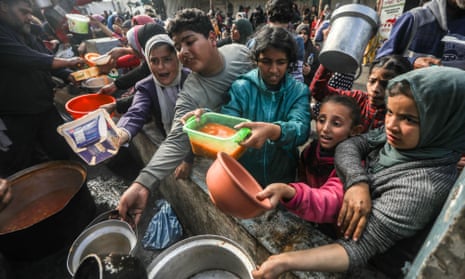 Palestinians queue to receive food at a makeshift charity kitchen in Rafah, on southern Gaza’s border with Egypt