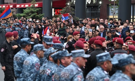 A line of police in the foreground with a crowd behind