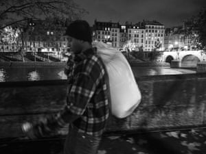 A man carrying bag over his shoulders walks along a riverside