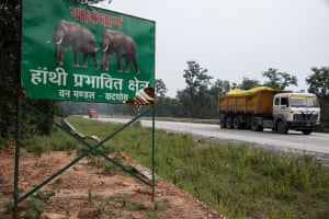 Coal trucks pass a sign on the highway through the Hasdeo Arand forest warning to beware of elephants. There are already a growing number of reports of incidences of human-elephant conflict as the elephants' habitat diminishes due to the open-cut coalmines.