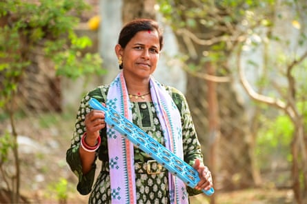 A woman holds a blue two-handled rattle studded with cymbals.