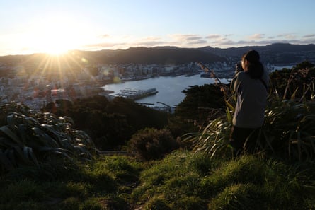 A woman takes a photograph of the city skyline from Mount Victoria in Wellington.