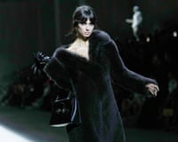 Model wearing a black fur coat that is slipping off a shoulder