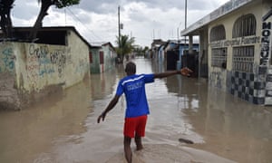 A man walks down a flooded street in the Cite Soleil area of Port-au-Prince