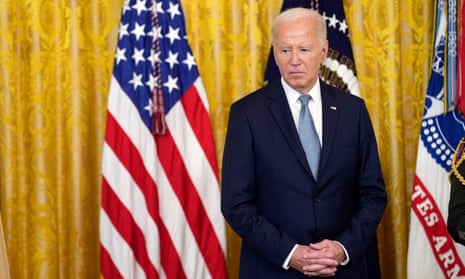 President Biden standing in front of American flags and a yellow curtain during a ceremony at the White House