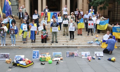 People stand with banners and hold toys on steps in protest at killing, kidnapping and deporting of Ukrainian children by Russia. 
