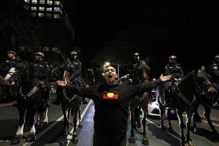 A protester stands in front of a police line during a march demanding action on Yuendumu deaths in police custody on 7 June in Sydney.