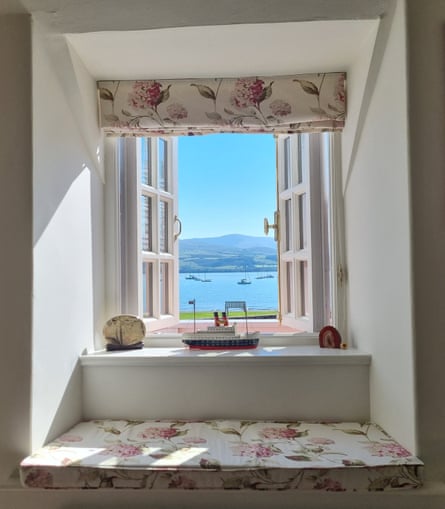 Boats on the sea and distant hills through the open window of Porth Hir cottage.