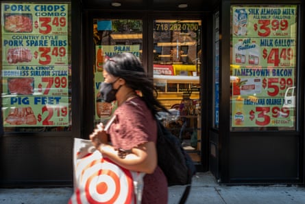 Woman walking past a food store with a food advertising sign outside