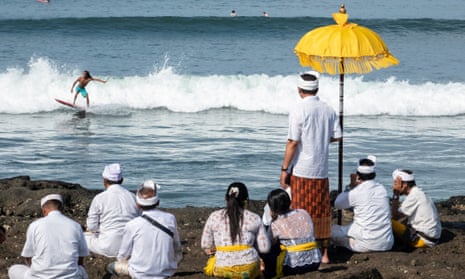 Hindus watch a surfer at the beach in Canggu