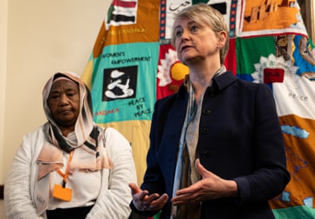 Yvette Cooper standing in front of a tapestry next to a woman in a Sudanese outfit