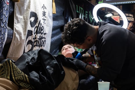 Manny in a black T-shirt and black latex gloves tattoos Chelsea