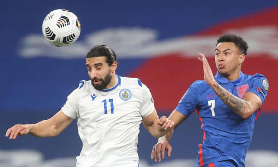 The San Marino defender Manuel Battistini heads the ball under pressure from the England midfielder Jesse Lingard.
