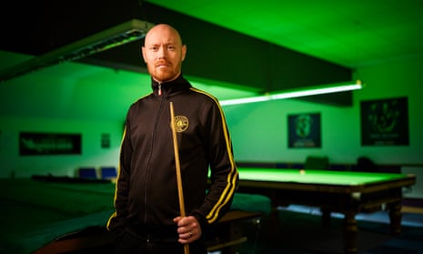 Gary Wilson stands holding his cue in front of a snooker table with green backlighting at his North Shields club.