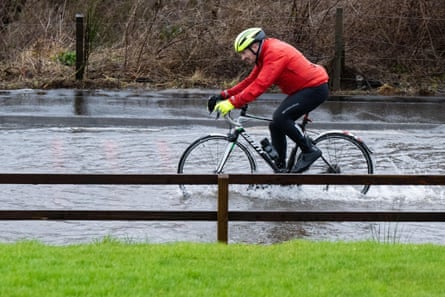 Un cycliste sur route déterminé au milieu des inondations sur la route A81 près de la distillerie Glengoyne en raison de l'eau de pluie qui s'écoule du sommet de Dumgoyne après les fortes pluies précédentes.  