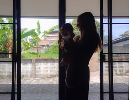 Lisa Young* holds her young daughter in front of some French windows. Their faces are mostly in darkness as they are silhouetted against the light outside