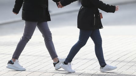 View of two pairs of legs in trainers walking