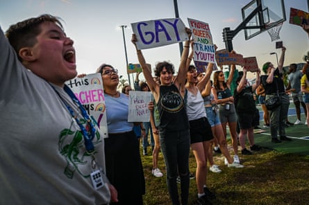 Students protest with LGBTQ+ rights signs.