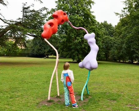 A child standing looking at a colourful sculpture by Vanessa da Silva
