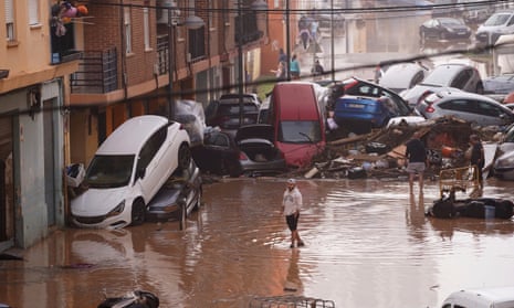 Residents look at cars piled up after being swept away by floods in Valencia, Spain.