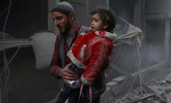 A man holds a child after airstrike in the besieged town of Douma in Syria