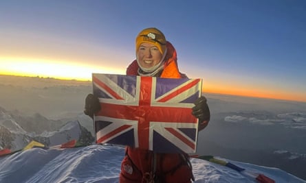 Brownlee holding a union flag at the summit of Nanga Parbat