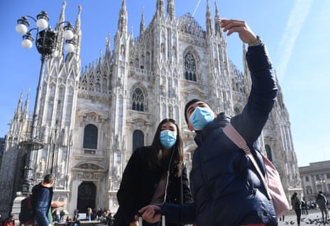 tourists in milan wear face masks as they take a selfie in front of the cathedral
