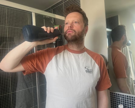 A man using a water flosser in his bathroom