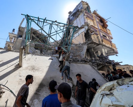 People remove a metal scaffolding from a building hit by Israeli bombardment