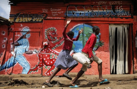 Children run past a mural featuring the coronavirus in the Kibera settlement in Nairobi, Kenya