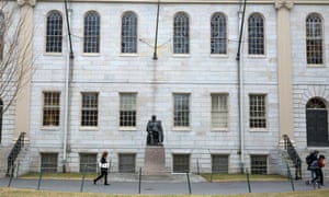 People walk past a statue of John Harvard on the university’s campus in Cambridge, Massachusetts