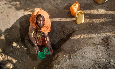 Sara, 50, scoops muddy water from a hand-dug well in hopes of bringing something home for her family to use in Ethiopia.