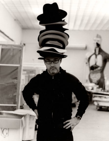 Damien Hirst with a tower of hats on his head