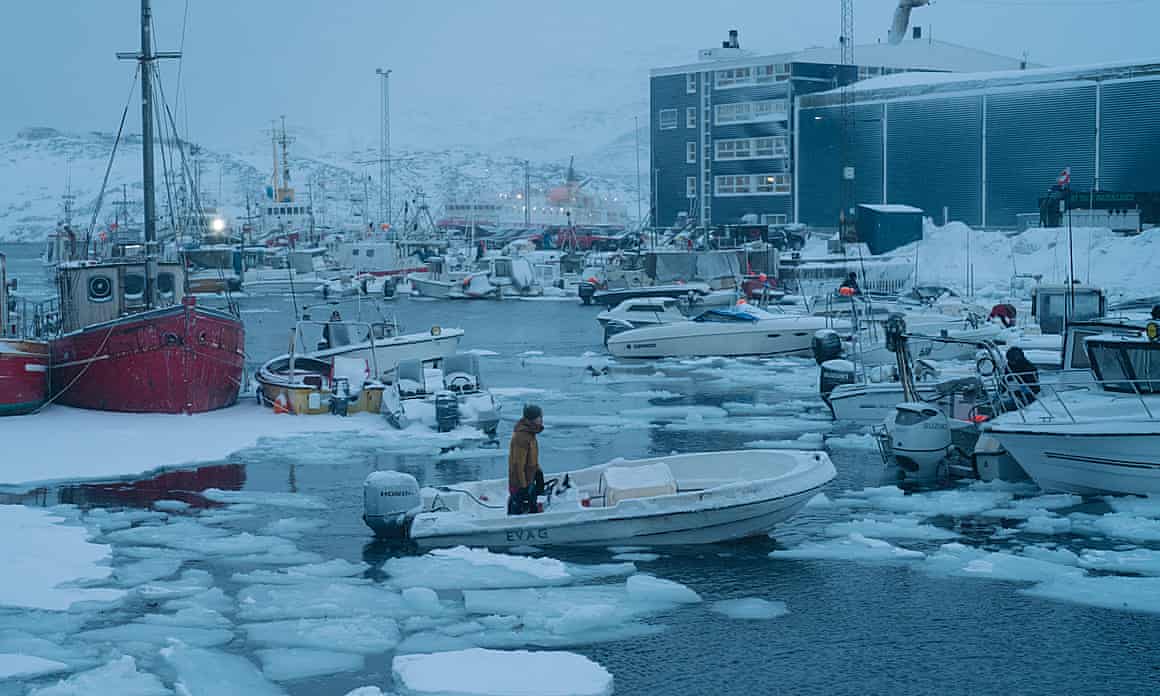 A fisher breaks the ice to enter the port of Nuuk
