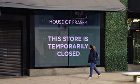 A woman with a face mask walking past a closed sign at House of Fraser department store