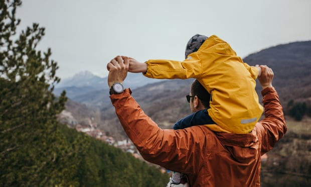 A man with child on his shoulders walking in mountains