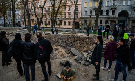 People gather by a rocket crater in central Kyiv on Wednesday after Russian strikes two days earlier. 