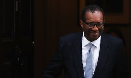 Kwasi Kwarteng smiling as he emerges from a doorway