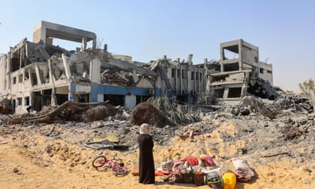 A woman looks around as she salvages items at the damaged Unrwa building complex in western Gaza City, 12 July 2024.
