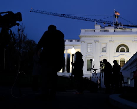 White House at dusk with media crews silhouetted in foreground