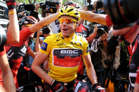 Cadel Evans celebrates with teammates and is surrounded by photographers after winning the Tour de France in 2011