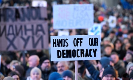 a sign saying hands off our democracy amid a large crowd of demonstrators