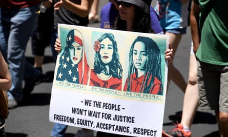 A protester in Sydney, Australia holds a placard with images from the We The People project designed by Shepard Fairey.