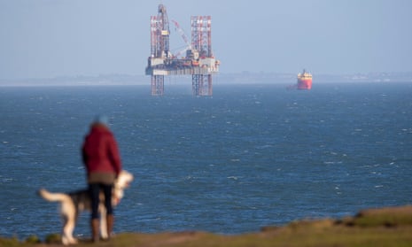A clifftop dog walker passes the ENSCO-72 drilling rig in Poole Bay, Dorset