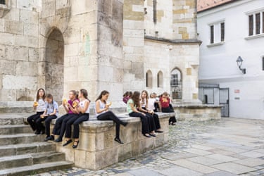 Young people sitting on a stone wall by a staircase