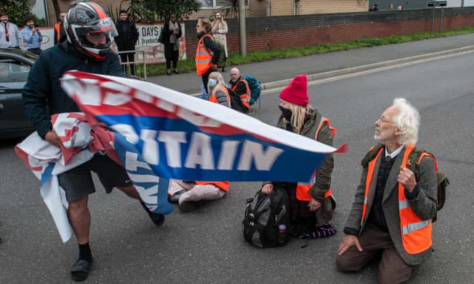A biker grabs a banner from an Insulate Britain protester in Thurrock, Essex