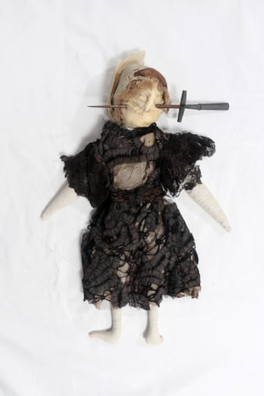 A ‘poppet’ of stuffed fabric in Edwardian-style black dress with stiletto through face, from 1909–13.