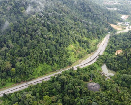 Aerial shot of a road cutting through dense Malaysian forest.
